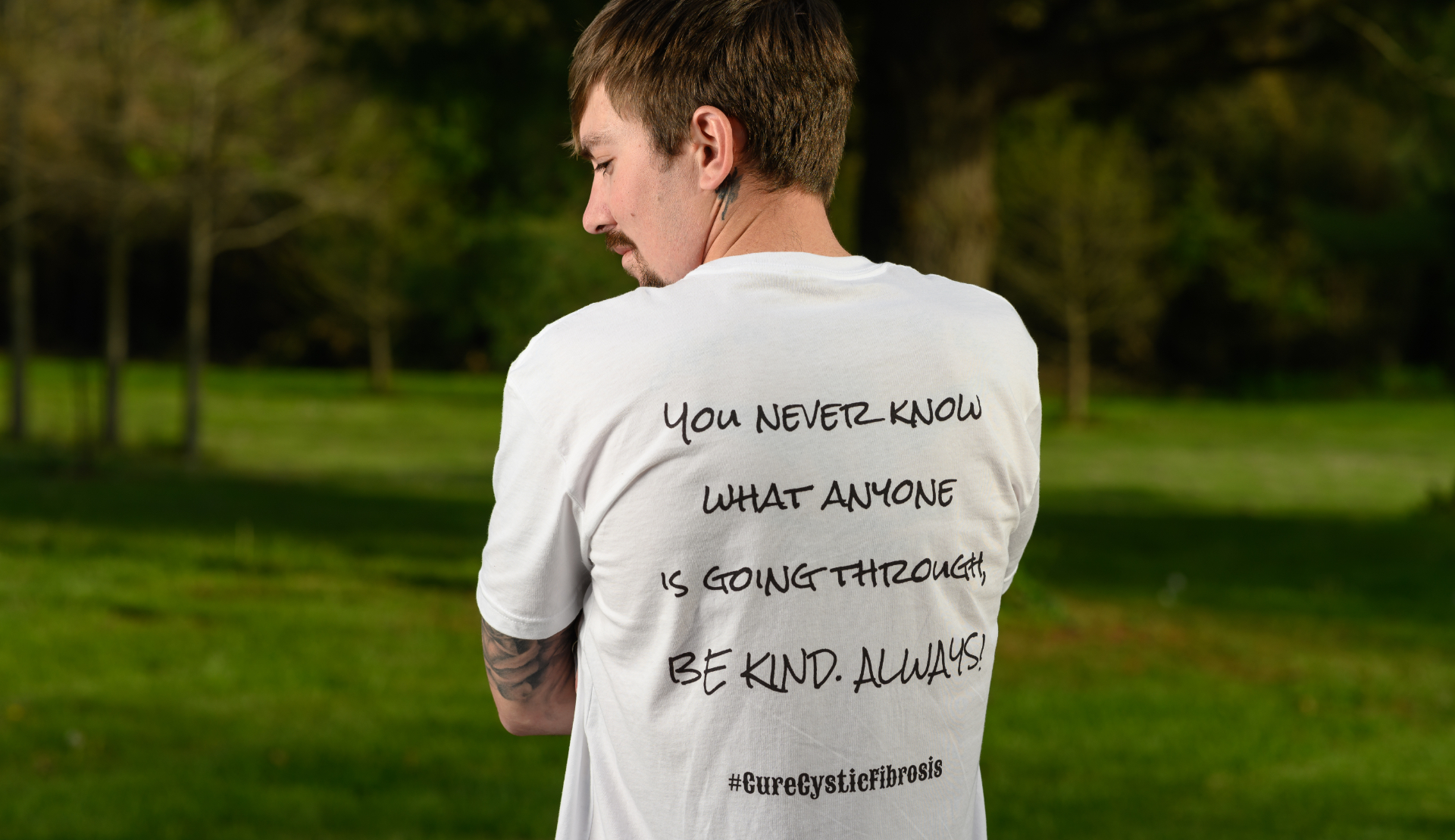 Cameron stands with his back to the camera displaying the phrase on the back of his shirt.