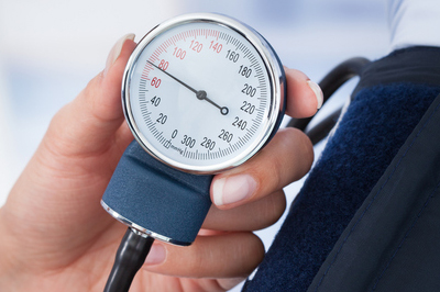 blood pressure cuff in use, being held in someone's hand