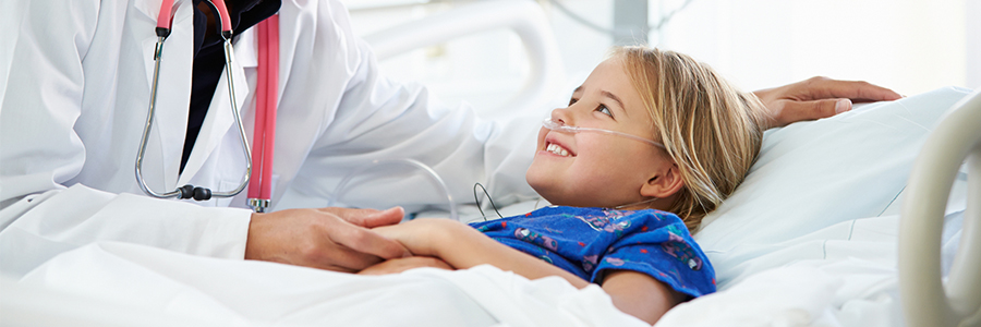 Doctor smiling at young girl in hospital bed