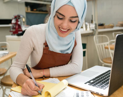 A young woman with a laptop works on her budget.
