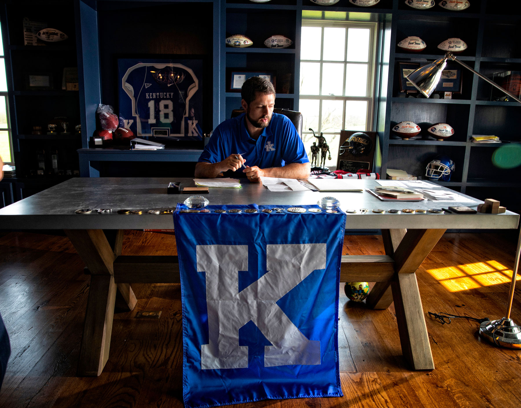 Jacob sits behind his desk which is decorated with paraphernalia from his football playing days.