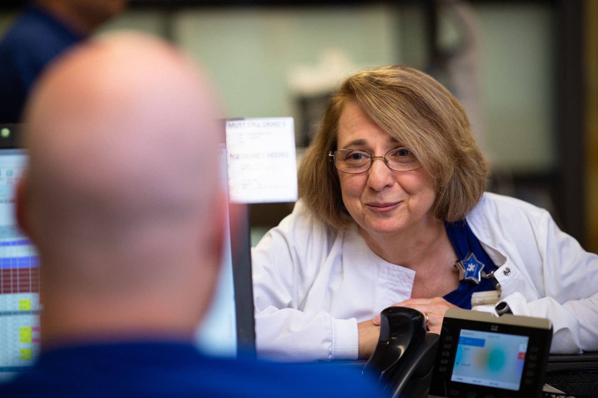 Margie leans over a desk to talk to the nurse behind the desk.