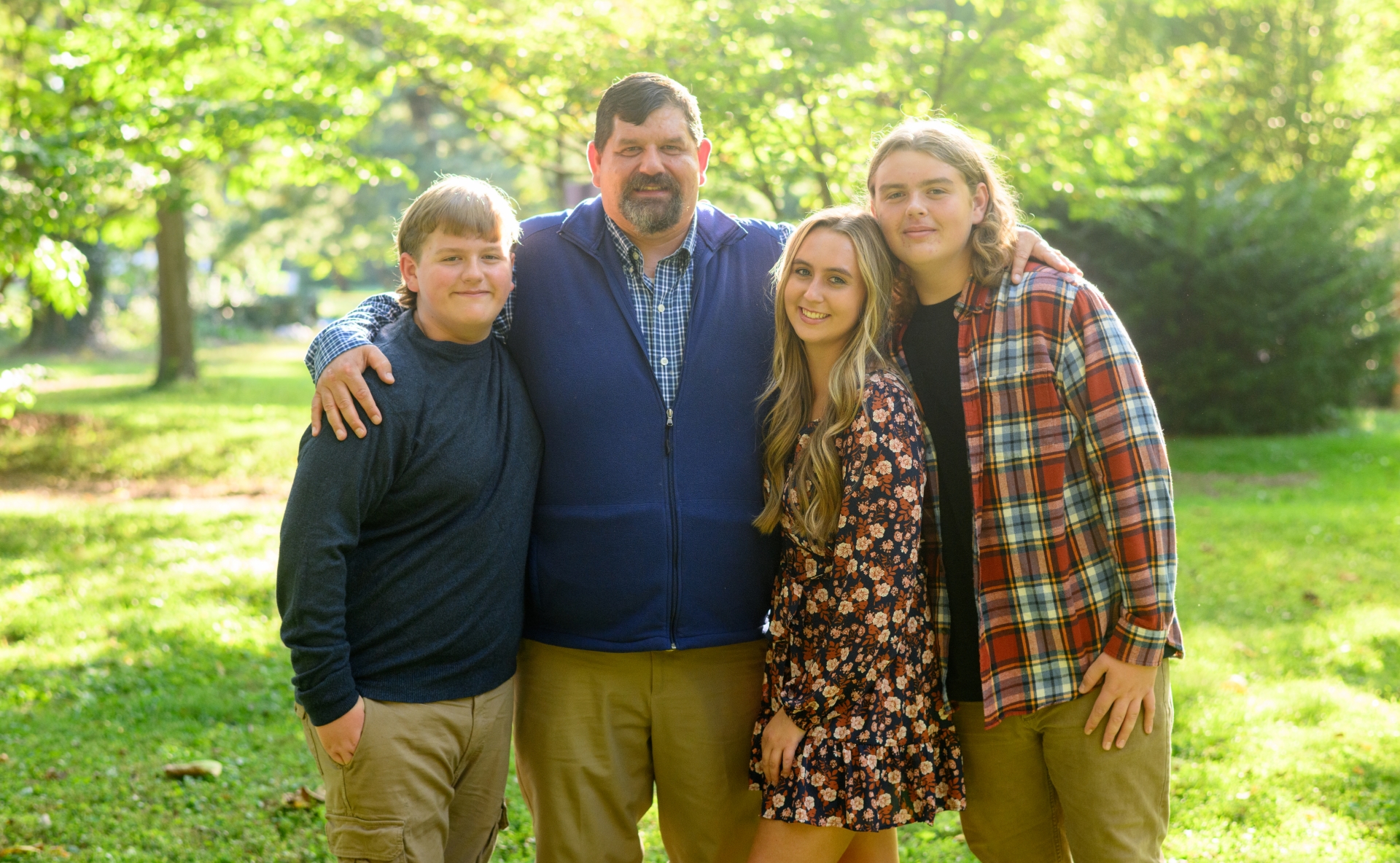 A photo of Ronald with his arms around his children as they pose together outside.