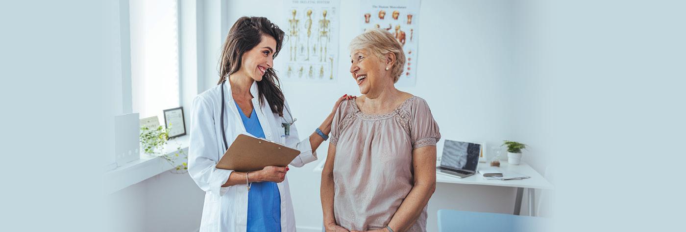 A woman and her doctor, who is also a woman, smile as they talk with one another.