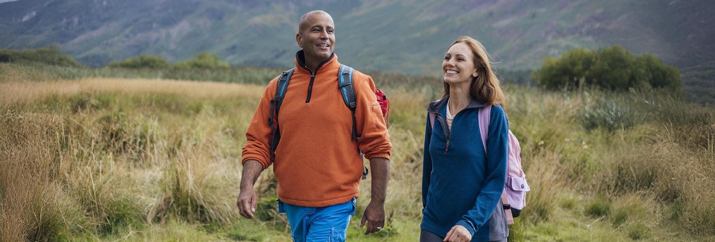 A man and woman smile as they hike together.