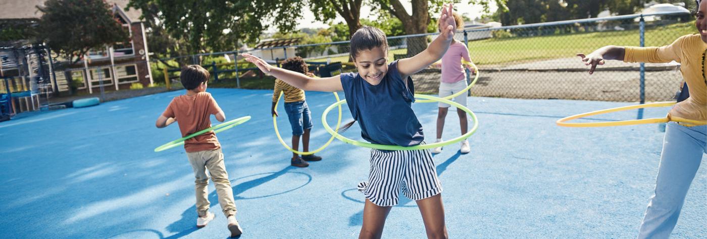 Children play with hula hoops in a schoolyard