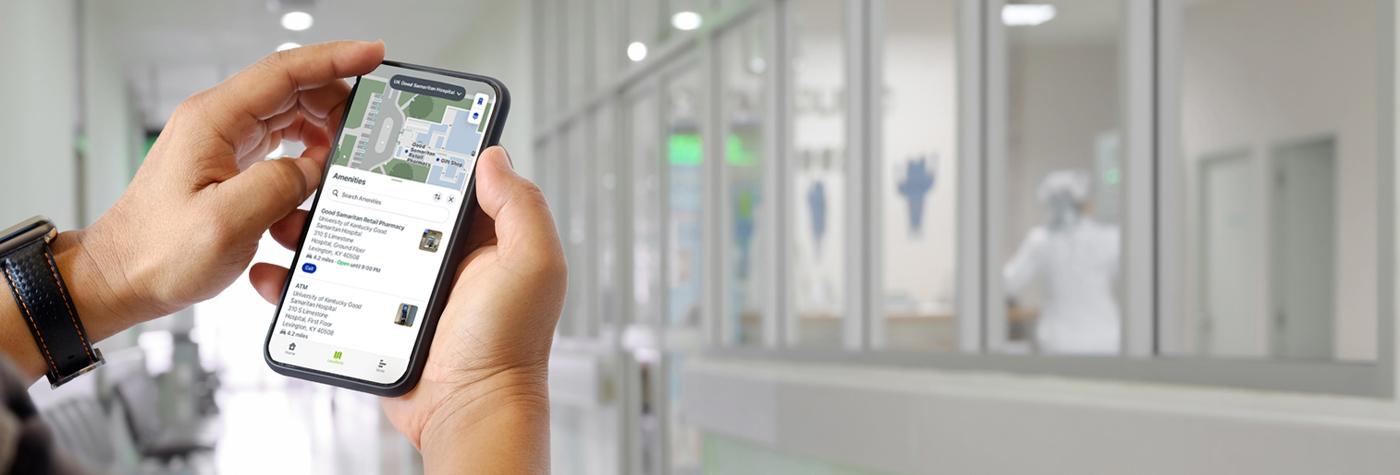 A closeup of two hands holding a smartphone with the Gozio wayfinding app on the screen. 