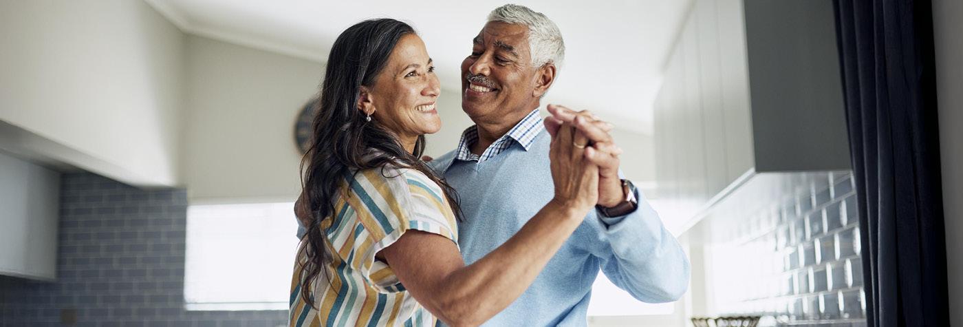 A man and woman dance together in a kitchen.