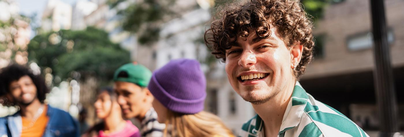 Smiling young man looking at camera near several friends