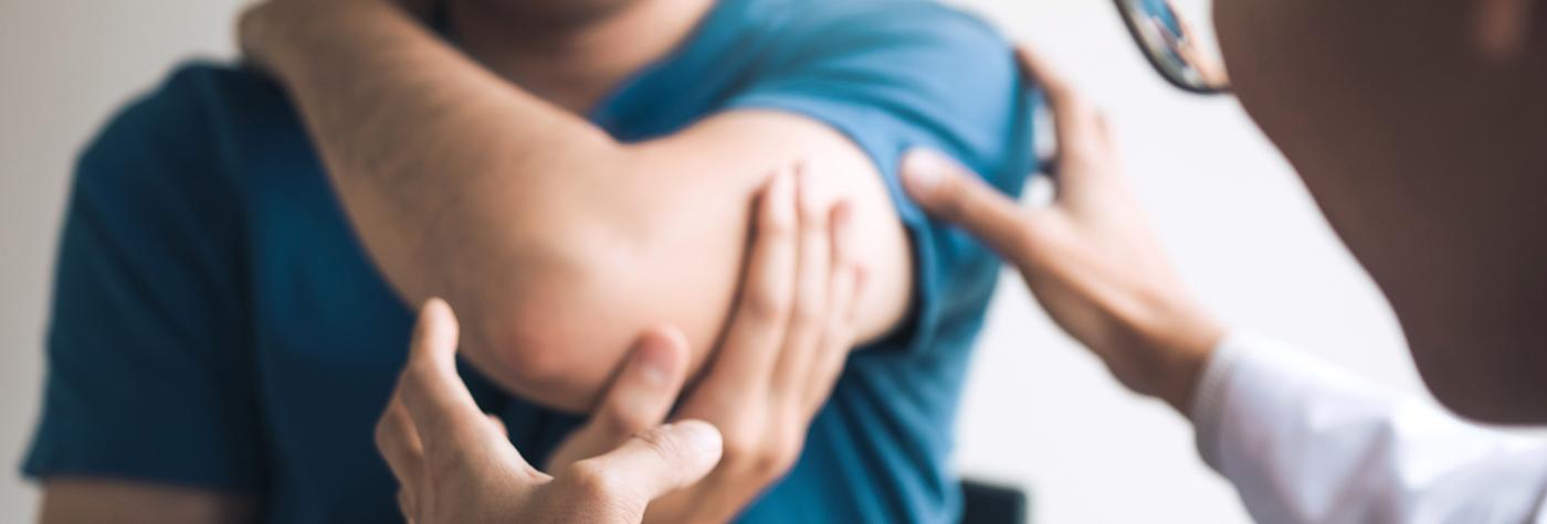 A doctor examines a patient's elbow.