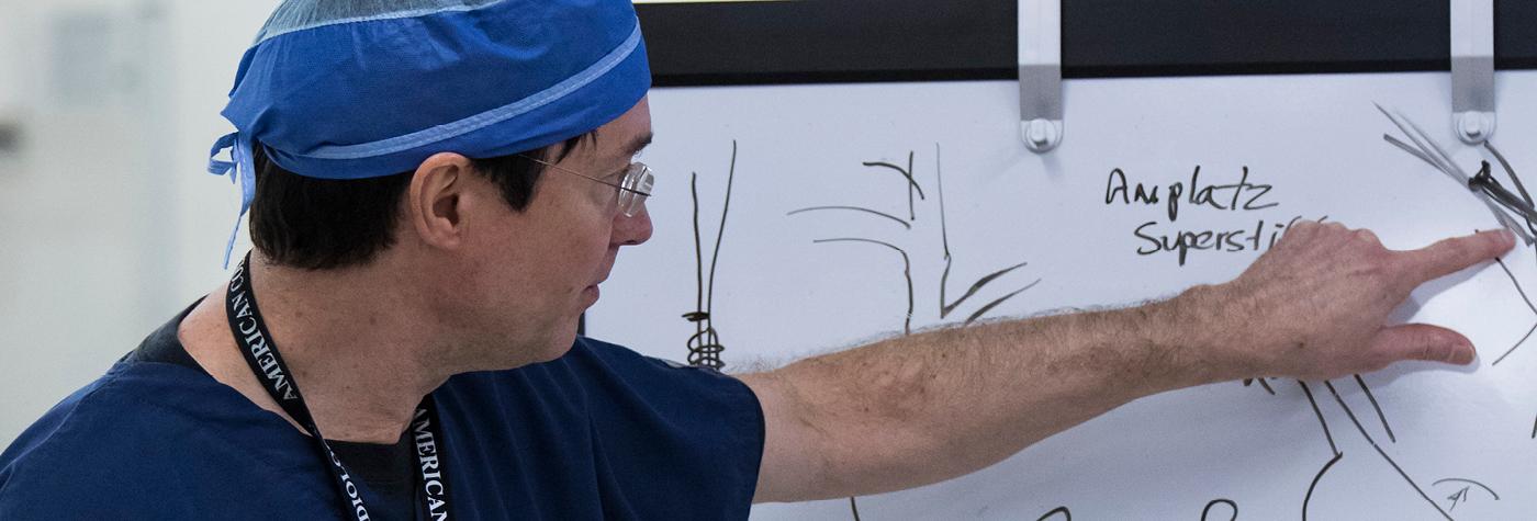 Dr. John Gurley motions towards a whiteboard.