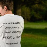 Cameron stands with his back to the camera displaying the phrase on the back of his shirt.