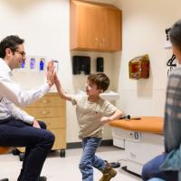 Granger Smith, center, gives a high five to Dr. David Neil Toupin, left, who's seated in a rolling chair. Granger's mother is slightly visible to the right.