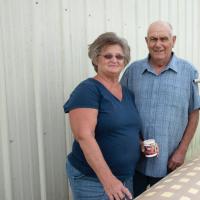 Charlotte and her husband pose together for a photo outside of their barn.