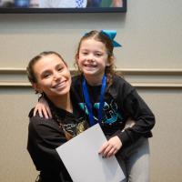Izzy hugs Sky Katz and they smile for a photo.
