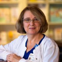 Margie leans against a shelf and smiles.
