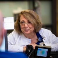 Margie leans over a desk to talk to the nurse behind the desk.