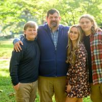 A photo of Ronald with his arms around his children as they pose together outside.